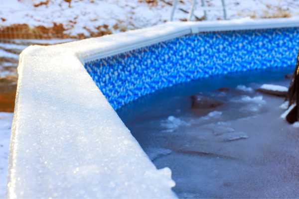 Frozen pool edge with icy surface and blue liner, illustrating winter pool maintenance for homeowners.